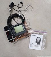 Photo showing the Lowrance X-4 fish-finder sonar device with attached cables and a plastic bag containing installation and operation instructions manual.