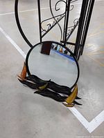 Mirror showing decorative metal boats with orange/yellow sails on wave-like black metal base.