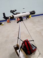 Full view of the National Geographic telescope mounted on a tripod with the red and black camera bag beside it.