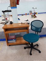 Oak laminate desk with office chair positioned in front, featuring binders on lower shelf and utensil holder on top.