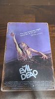 Metal poster sign depicting the movie 'The Evil Dead' with horror theme artwork and text