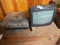 Atari console and Symphonic Television CRT TV on wooden crate showing full items in lot.