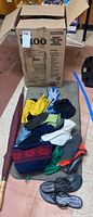 Lot items laid out on floor showing gloves, caps, sandals and umbrella near cardboard box