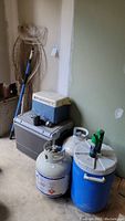 Photo of coolers, propane tanks, blue insulated cooler with bug spray on top