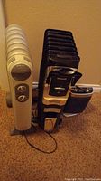 Three heaters shown vertically: white Patton radiator heater on left, black Honeywell radiator heater in the center, and part of a third heater behind.