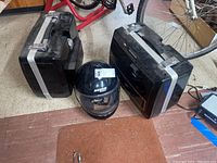 Two black Hondaline motorcycle saddlebags with silver trim and a black Nolan full-face helmet with clear visor, all set on floor.