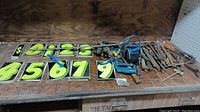 Lot showing bright yellow number plates numbered 0 to 9 alongside various hand tools including a blue handled tool and hammer