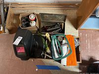 Photo showing a top view of the lot featuring welding helmet, hammer, sanding wheels, measuring tape, and other tools.