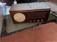 Side view of the vintage Sparton radio showing wooden cabinet, cloth-covered speaker grille, and tuning dial with knobs.