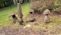 All four carved wooden mushrooms arranged on grass, showing full set.