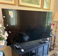 Front view of 65-inch Samsung TV on stand with two remotes