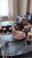 Table display showing all items in the lot: teapot with cups on gold tray, two vases, decorated plates, and tall lidded mugs.
