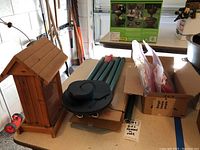 Wooden hanging bird feeder, metal wind chimes parts, and boxed hummingbird feeders displayed on table.
