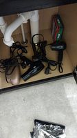 Photo showing four hair dryers of different colors and styles under a sink area