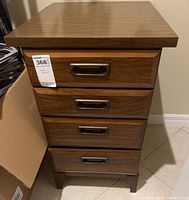 Front view of wooden dresser with all four drawers closed showing metal handles and medium brown finish.