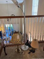 Floor lamp and three table lamps grouped together by railing in a room.