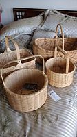 Four hand made white oak baskets displayed on a bed, showing size and handle variations.