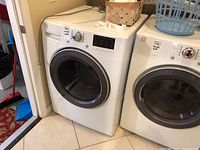 Photo showing white front load Kenmore washer next to dryer, tiled floor.