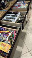 Three open kitchen drawers showing organized Reed & Barton flatware in the middle drawer, other drawers filled with miscellaneous household items