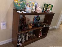 Wide view of wooden shelf with assorted knick-knacks including Easter baskets, animal figurines, and small decorative items