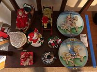 Top-down view of the lot showing all music boxes on a wooden table including dolls, rocking horse, Santa, figurines, and carousel horse plaques.