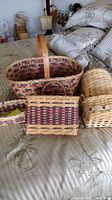 Photo showing five handmade baskets on a patterned surface, displaying various woven styles and colors.