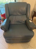 Front view of the blue gray leather recliner rocker chair showing padded seat, back, and armrests with nailhead trim.