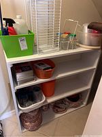 Shelf with cleaning supplies, containers, paper goods, and dishes arranged on shelves.