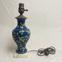 Full front view of the antique cloisonne vase lamp showing the blue vase with gold floral leaf patterns, brass lamp fitting, and white marble base with electrical cord.