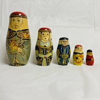 Front view of all five Asian nobility nesting dolls lined up from largest to smallest showing intricate painted details on faces and traditional clothing.