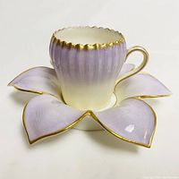Front-side view of the Carlsbad porcelain teacup and flower-shaped saucer showing gradient color and gold trim details