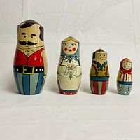 Front view of four wooden family nesting dolls, hand-painted with folk art style faces and colorful clothing