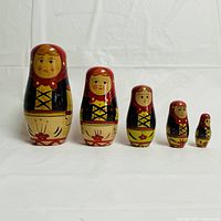 Front view of five ginger babushka nesting dolls arranged by size showing detailed facial designs and floral dresses