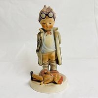Front view of the Goebel Hummel Doctor figurine showing the boy in a doctor outfit standing over a doll.