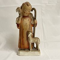 Front view showing shepherd boy with lamb on shoulders and a lamb at feet.