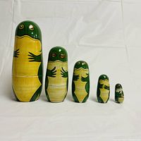 Front view of 5 green lizard Russian nesting dolls arranged largest to smallest showing detailed faces and front body design.