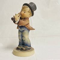 Side view of the Hummel Serenade figurine showing the boy playing a clarinet with a top hat and detailed clothing.