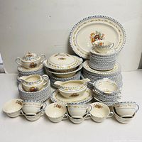Full view of all over 80 pieces neatly stacked showing various plates, bowls, teacups, saucers, gravy boats, and covered serving dishes with floral and blue checkered pattern.