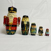 Front view of five hand-painted sea captain Russian matryoshka nesting dolls arranged in descending size from left to right on white background.