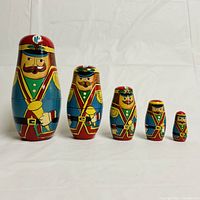 Front view of five painted wooden toy soldier nesting dolls arranged in descending size order