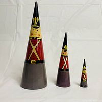 Three toy soldier nesting dolls arranged largest to smallest showing front detail painted faces, coats, and hats.