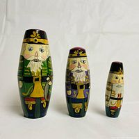 Front view of three wooden toy soldier nesting dolls showing detailed faces, hats, and uniform fronts with yellow gold swords.