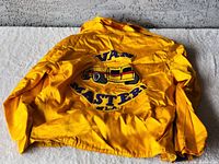Full view of the back of the bright yellow Van Masters jacket showing embroidered van patch and text