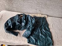 Green leather jacket and matching skirt laid flat on a surface, showing the entire outfit.