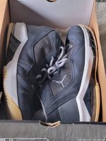 Pair of black Air Jordan sneakers inside their box, showing wear and creasing