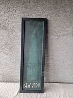 Front view of rectangular metal wall sign with black frame, embossed Chrysler Building and 'New York' text.
