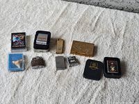 Wide view of all lighters and cigarette case included in the lot.