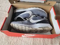 Pair of Nike sneakers inside original red and white Nike box, showing overall condition and box wear.