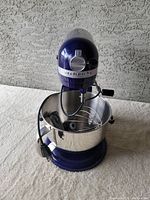 Front and side view of the purple KitchenAid Professional 600 stand mixer with stainless bowl and attached cord.