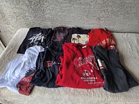 Full lot of 8 graphic t-shirts folded and laid out showing variety of colors and prints.
